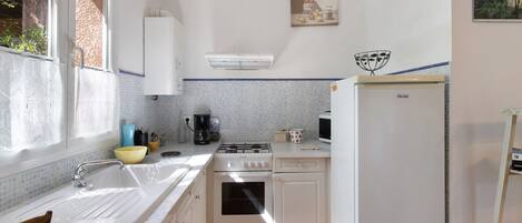A kitchen with a sink, stove, oven, and refrigerator.