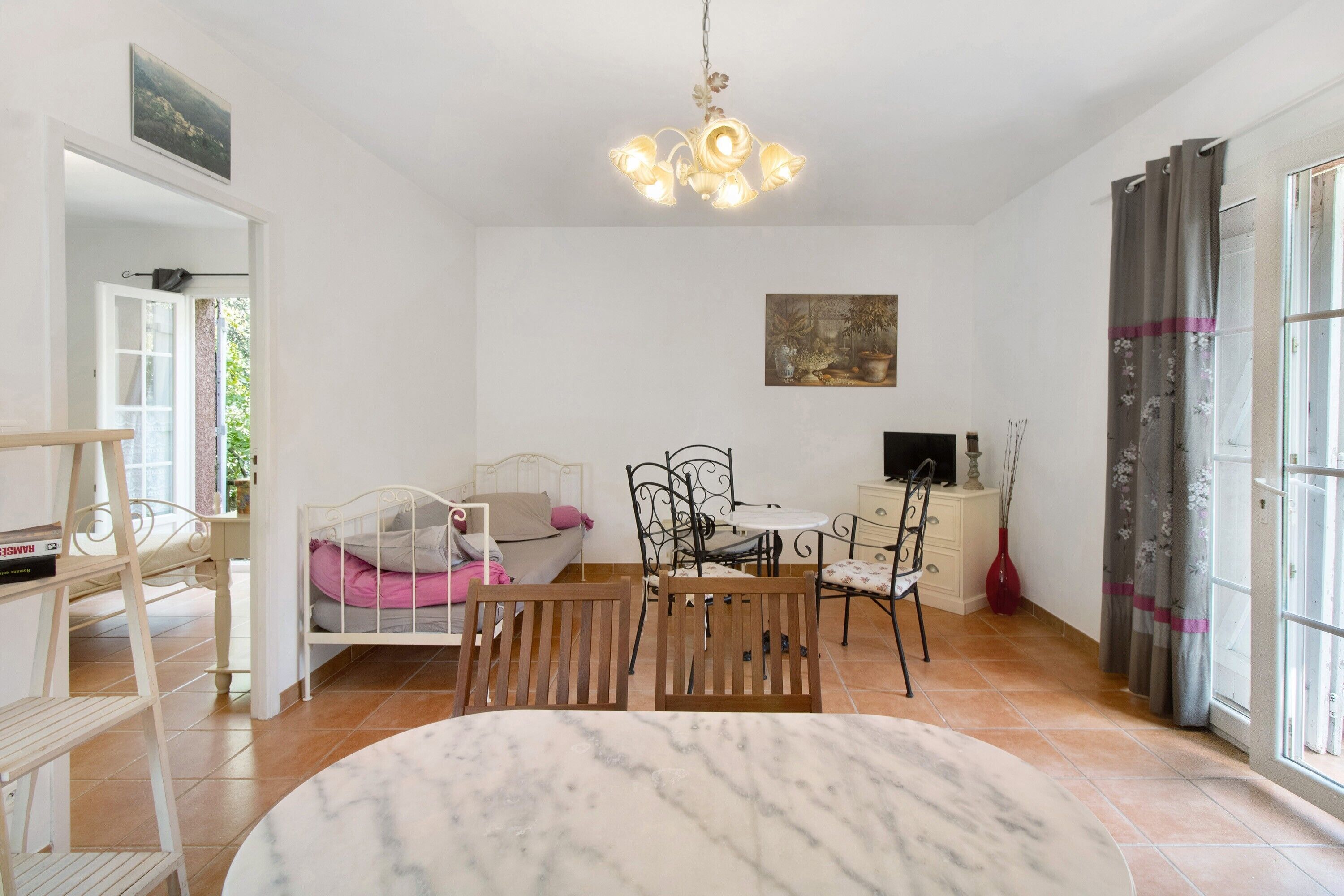 A room with a bed, a dining table with chairs, a TV, and a painting on the wall.