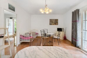 Una habitación con una cama, una mesa de comedor con sillas, un televisor y un cuadro en la pared.
