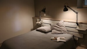Ein ordentlich bezogenes Bett mit Kissen, ein Nachttisch mit Lampe und ein Buch darauf.