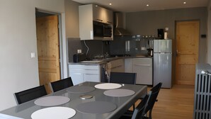 Eine moderne Küche mit Essbereich, inklusive Tisch mit Stühlen, einer Mikrowelle, einem Herd und einem Kühlschrank.