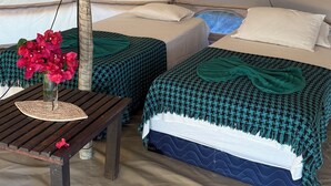 Una carpa con dos camas, una mesa con un florero y una lámpara.