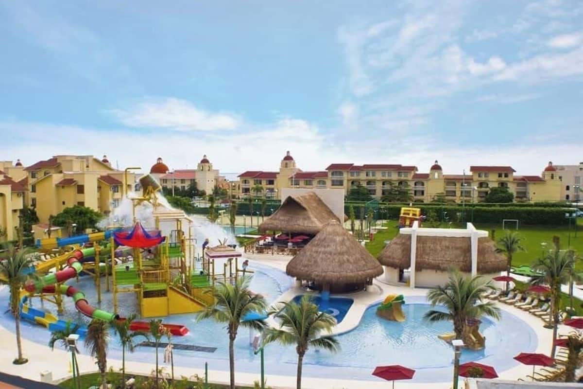 Un resort con parco acquatico, strutture a tetto di paglia e area piscina.