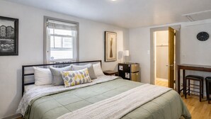 Un dormitorio con cama, escritorio, silla, reloj y ventana.