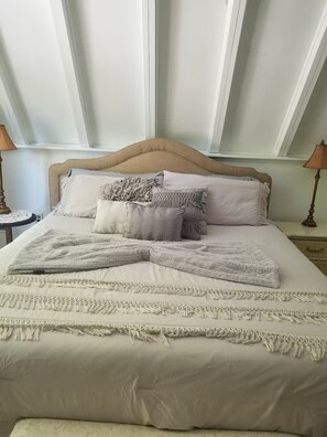 A neatly made bed with a headboard, multiple pillows, and a blanket.