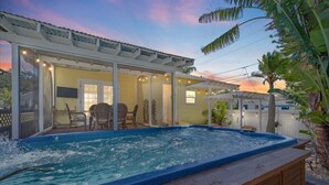 Een hottub met een houten terras, een overdekte patio en uitzicht op de ondergaande zon.