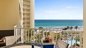 A balcony with a view of the beach and pool, a cooler with drinks, and a chair. - Shores of Panama 3BR Beachfront Condo w/ Same-Floor Parking & Resort Amenities (Panama City Beach)