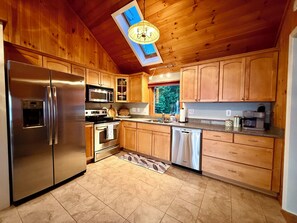 Una cocina moderna con armarios de madera, electrodomésticos de acero inoxidable y un tragaluz.