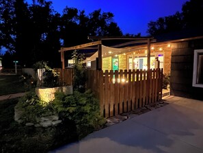 A house with a wooden fence, a paved driveway, and a well-lit entrance.