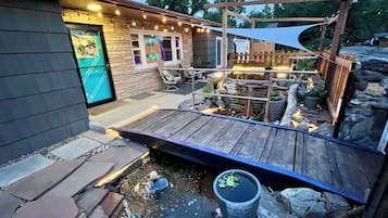A patio area with a wooden deck, a small pond, and a stone wall.