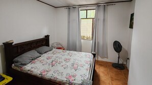 A bedroom with a bed, a window with curtains, a standing fan, and a tiled floor. - Howler Monkey Sunset House / Just 200 mts from the Beach and Sunsets (Guanacaste Province)