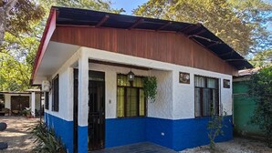 A single-story building with a flat roof, a front porch, and a small front yard. - Howler Monkey Sunset House / Just 200 mts from the Beach and Sunsets (Guanacaste Province)