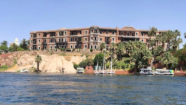 Un hotel de varios pisos, costa rocosa y barcos en el agua.
