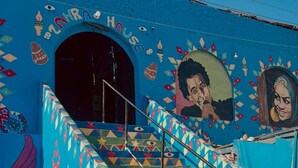 Una escalera con patrones geométricos coloridos y un mural con el retrato de una mujer.