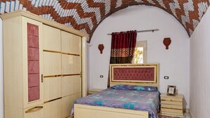 Un dormitorio con cama, armario y un arco decorativo en la pared.