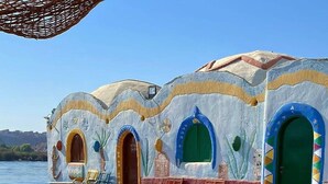 Un edificio frente al mar con fachadas coloridas, mesas al aire libre y vistas al agua.