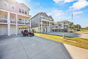 A residential area with multi-story houses, a paved driveway, and a fire hydrant. - Golf Cart Included + Close to Beach and Restaurants! (Carolina Beach)
