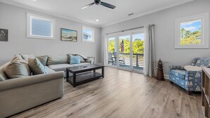 A spacious living room with a ceiling fan, a sofa, a coffee table, and a patterned armchair. - Golf Cart Included + Close to Beach and Restaurants! (Carolina Beach)