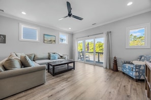 A spacious living room with a ceiling fan, a sofa, a coffee table, and a patterned armchair. - Golf Cart Included + Close to Beach and Restaurants! (Carolina Beach)