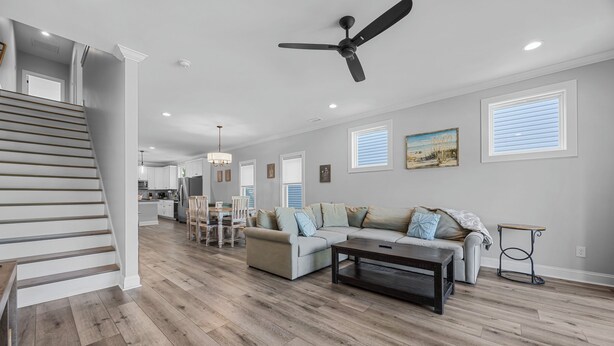 A spacious living area with a staircase, a ceiling fan, a dining area, and a kitchen in the background. - Golf Cart Included + Close to Beach and Restaurants! (Carolina Beach)