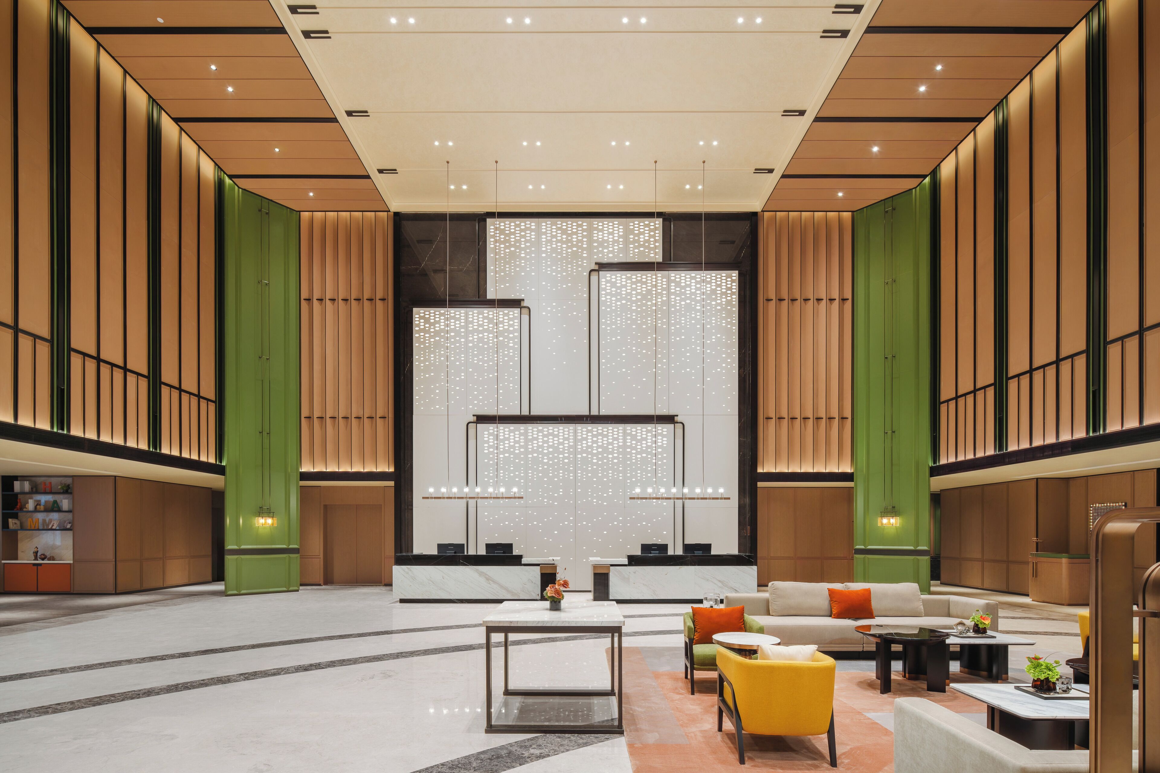 A spacious lobby with a reception desk, seating area, and a decorative wall with vertical panels.