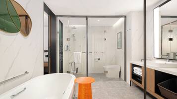 A modern bathroom with a bathtub, shower, and toilet, featuring marble walls and a glass shower enclosure.