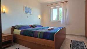 Une chambre à coucher avec un lit en bois, une table de chevet, une armoire, une fenêtre avec des rideaux et des lampes fixées au mur.