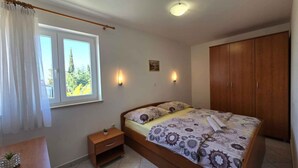 Une chambre à coucher comprenant un lit, des tables de chevet, une armoire, une fenêtre avec des rideaux et des lampes fixées au mur.