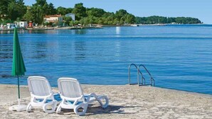 Une plage avec des chaises longues, une piscine et une vue dégagée sur l’eau.