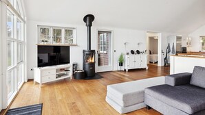 En rummelig stue med pejs, fjernsyn og sofa.