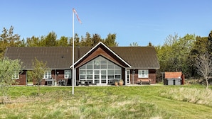 En bygning med stor glasfacade, flagstang og en græsplæne foran.