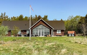 A building with a large glass front, a flagpole, and a grassy area in front.