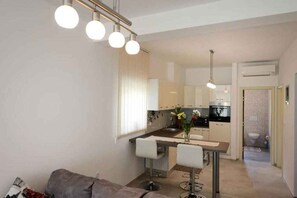 Eine moderne Küche mit weißen Schränken, einem Essbereich mit Tisch und Stühlen sowie einer kleinen Barzeile.