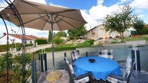 An outdoor patio with a table and chairs, a large umbrella, and a view of a residential area. - Holiday apartment with shared pool (Poreč)