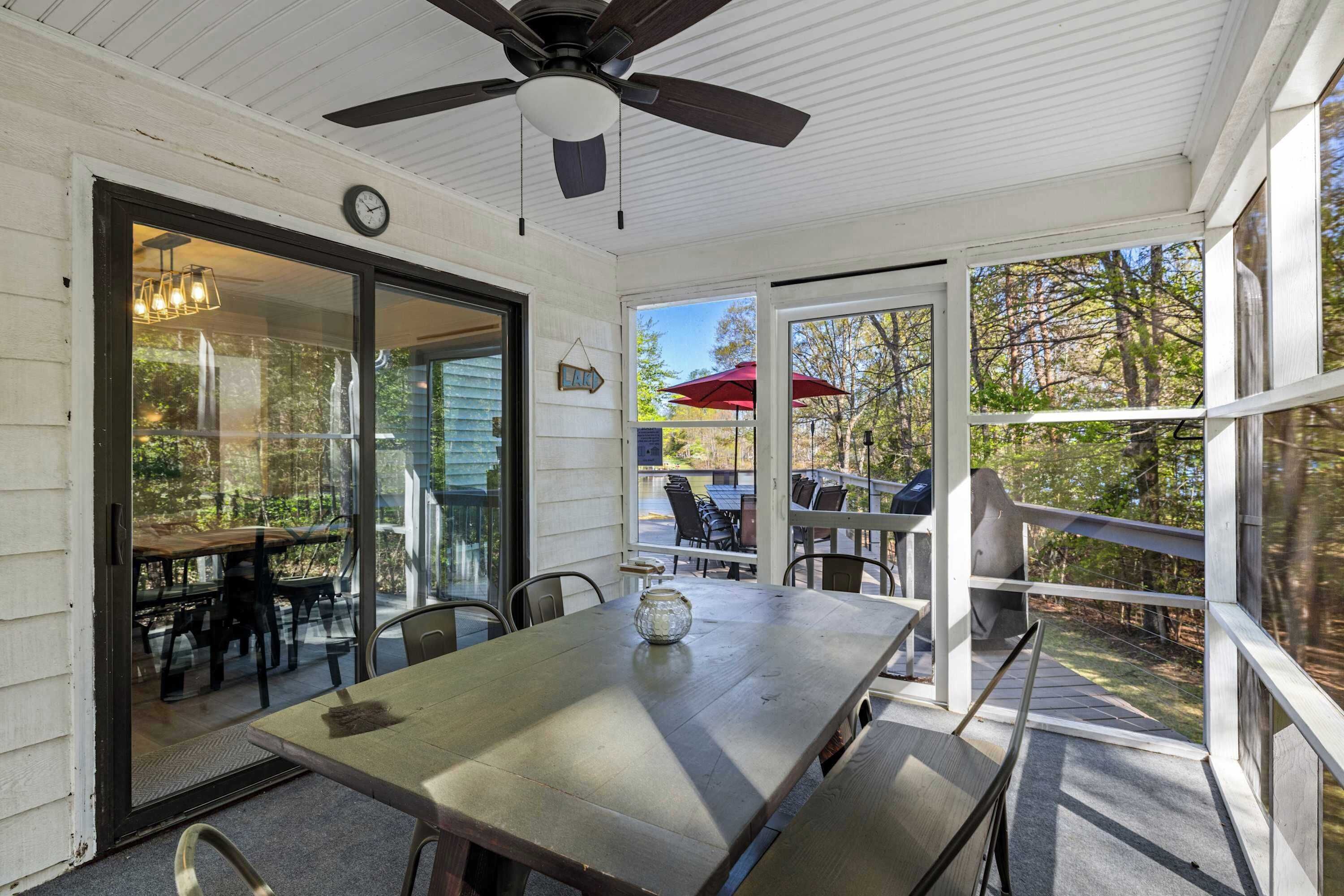 Une terrasse extérieure avec une table, des chaises, un ventilateur de plafond et une vue sur le jardin arrière.