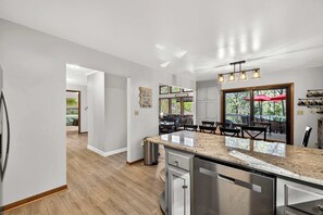 Una cocina moderna con encimera de granito, electrodomésticos de acero inoxidable y comedor con mobiliario de exterior.