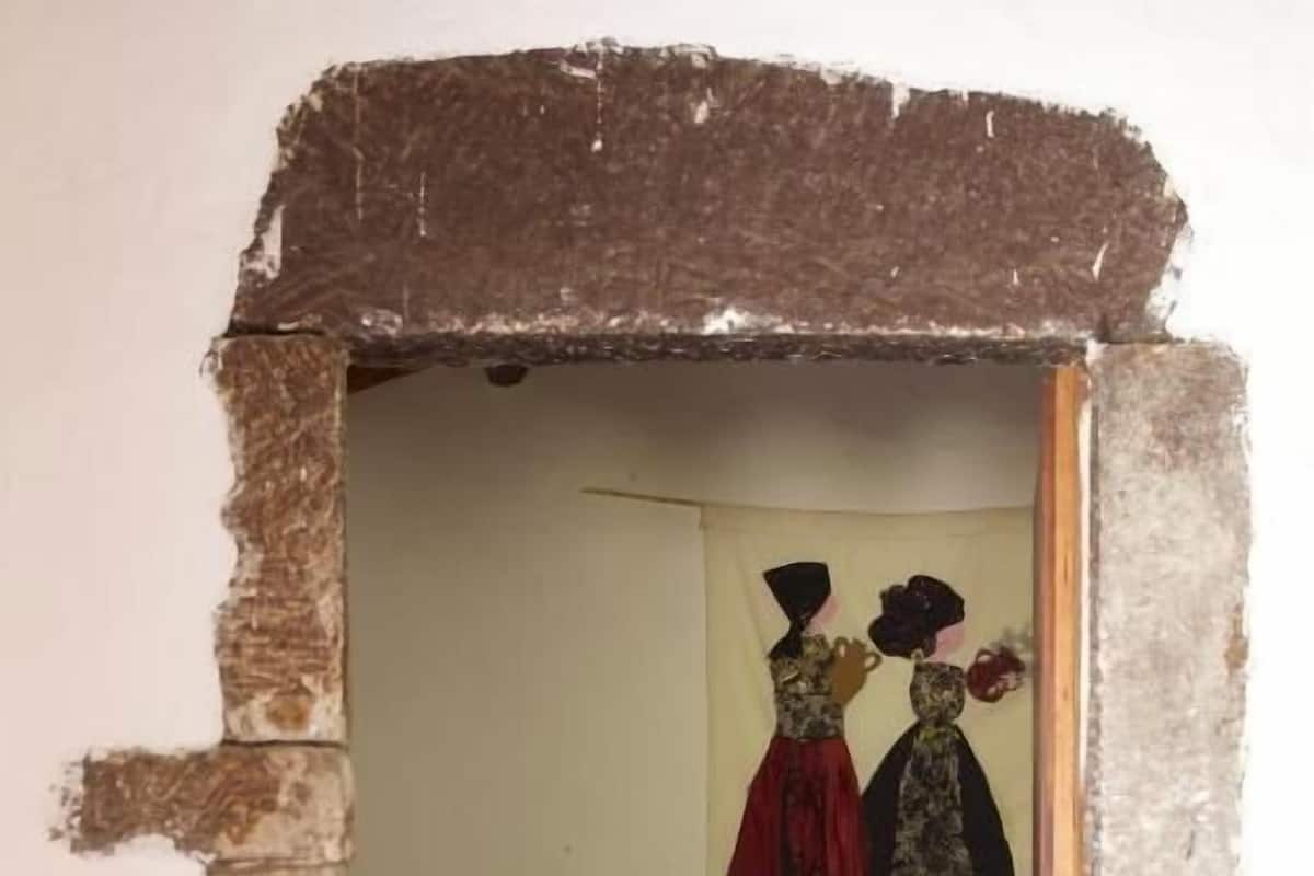 Une chambre à coucher avec un lit, une table de chevet et un miroir fixé au mur.