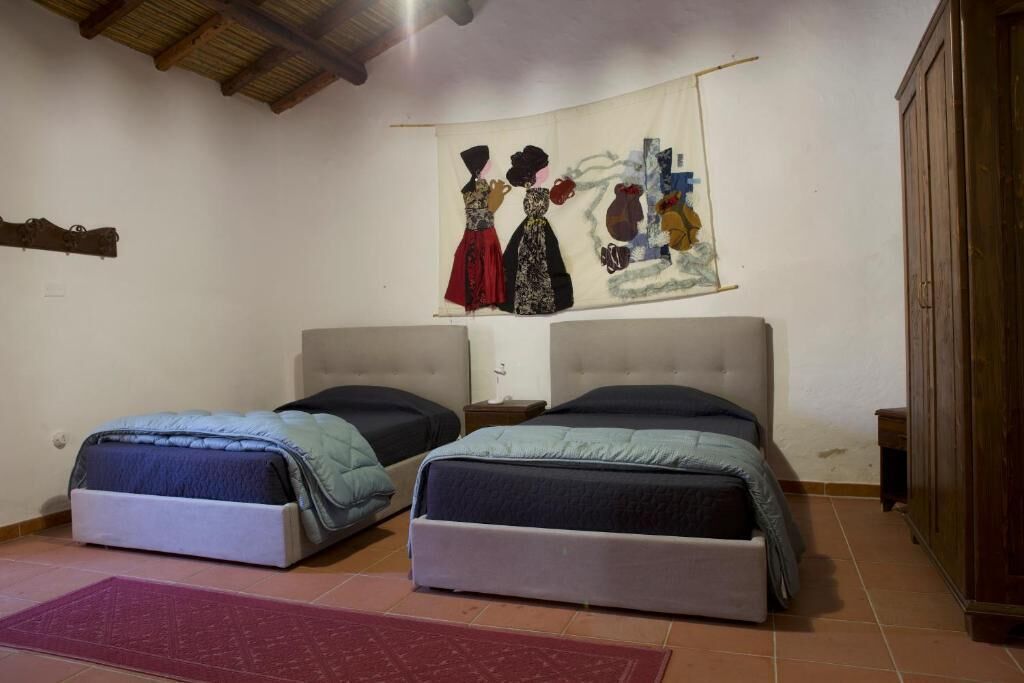 Un dormitorio con dos camas, un armario de madera y un tapiz en la pared.