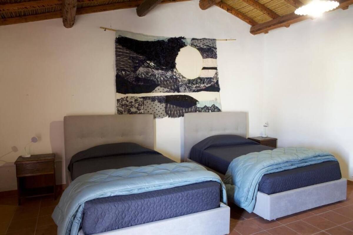 Une chambre avec deux lits, un plafond en bois et une tapisserie au mur.