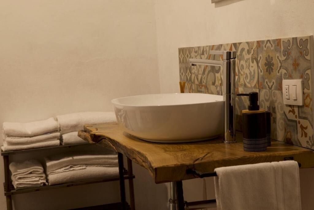 Un baño con un lavabo de pedestal, un mueble de tocador de madera y toallas dobladas con esmero.