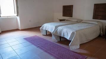 A room with two beds, a window, and a purple rug.