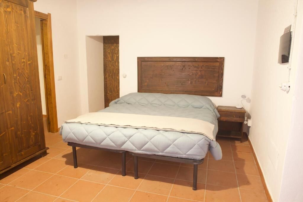 A bedroom with a bed, wooden headboard, bedside table, and a wardrobe.