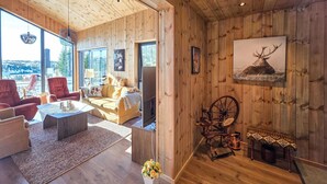 Un salón amplio con paredes de madera, un ventanal grande y un rincón de descanso acogedor.