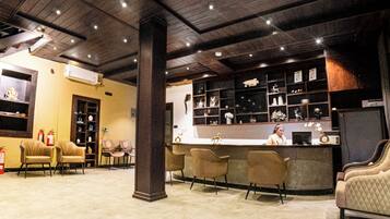 A lobby with a reception desk, several chairs, a fire extinguisher, and a decorative wall with shelves.
