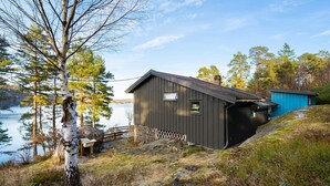 A cabin by a lake with a dock, surrounded by trees. - Nice home in Risør with house sea view (Risør)