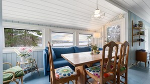 A cozy room with a wooden dining table, blue sofa, and wicker chairs. - Nice home in Risør with house sea view (Risør)