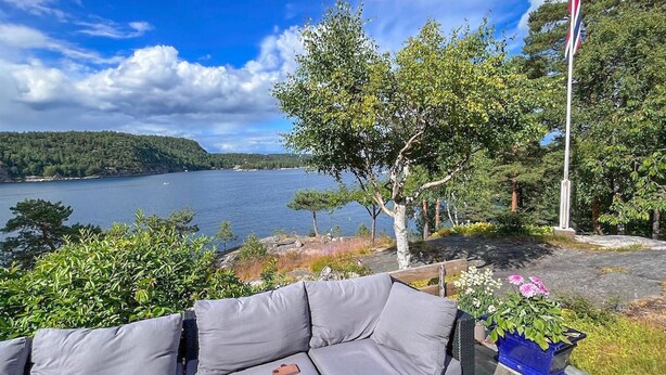 A patio with a grey sofa, a blue flower pot, and a flagpole. - Nice home in Risør with house sea view (Risør)
