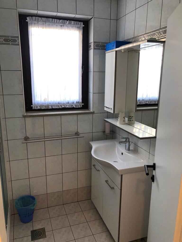 A small bathroom with a window, a sink, and a mirror.