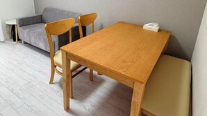Una habitación con una mesa de comedor de madera, dos sillas, un sofá gris y una mesita redonda.