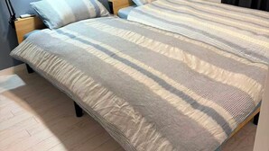 Una cama con colcha a rayas, una lámpara de noche y una mesita.